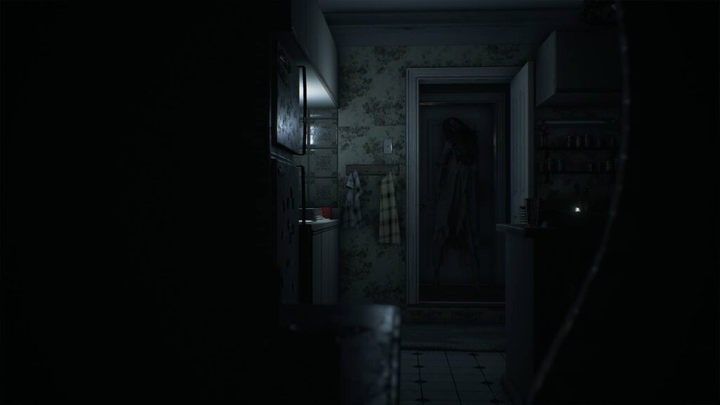 Visage: Hororová dívka prochází otevřenými dveřmi do kuchyně.