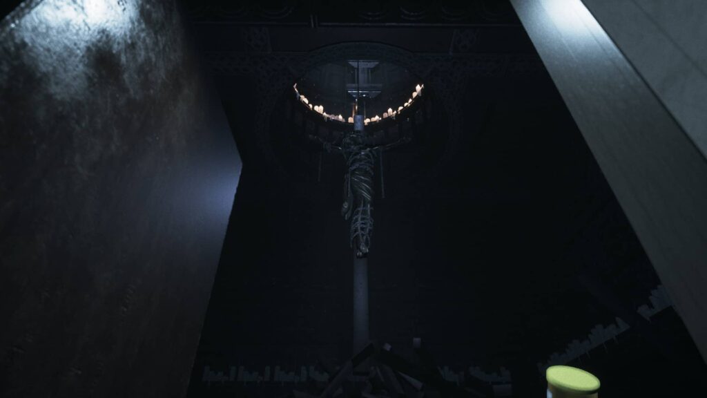 Visage: Postavený kříž s ukřižovanou postavou omotanou řetězy. Nad křížem zeje ve stropě díra obklopená hořícími svíčkami.